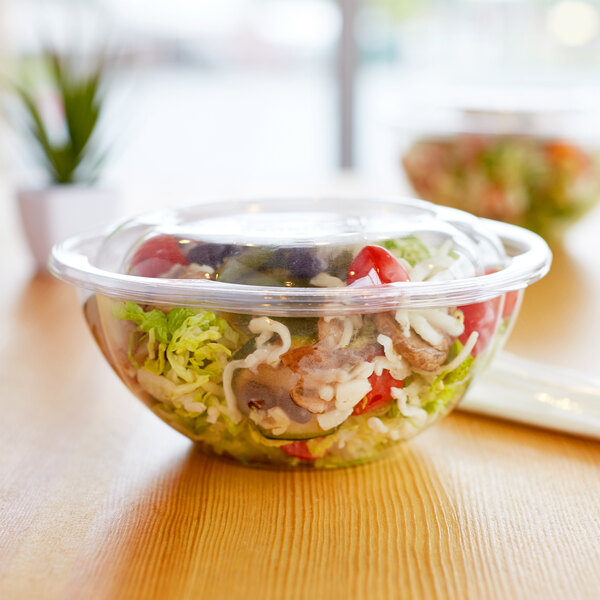 A clear plastic Eco-Products salad bowl filled with salad on a table.