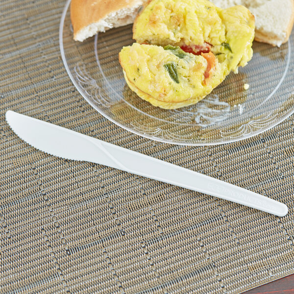 A plate of food with a sandwich and a white compostable plastic knife on it.