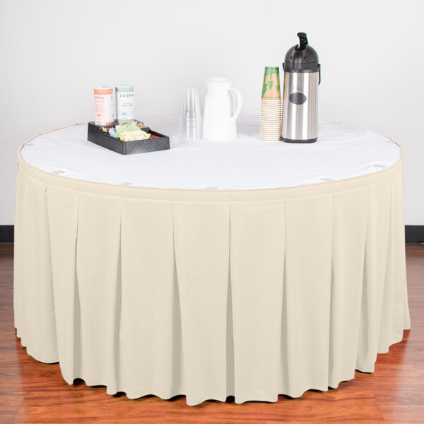 A table with a Snap Drape bone table skirt on a white table with food.
