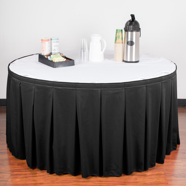 A table with a black Snap Drape table skirt and a tray of drinks.