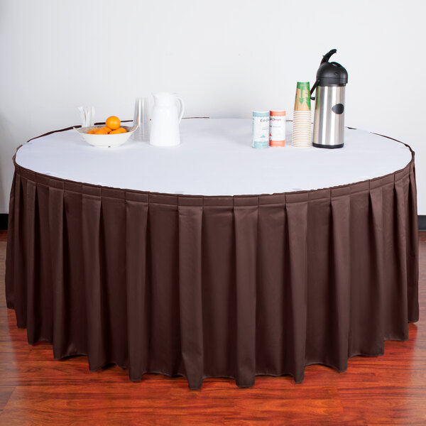A table with a brown Snap Drape table skirt and a thermos.