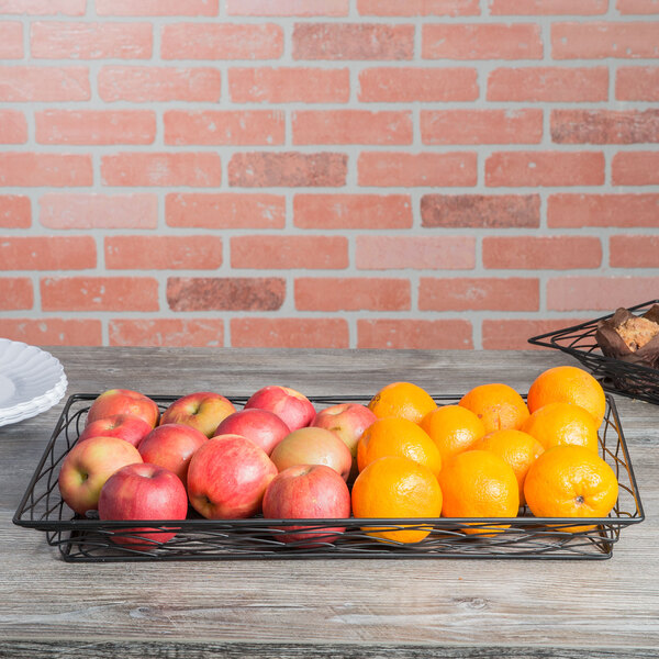 A rectangular black metal basket filled with apples and oranges on a table.