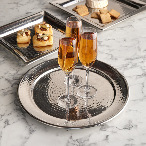 An American Metalcraft stainless steel hammered tray holding food and glasses of champagne on a table.