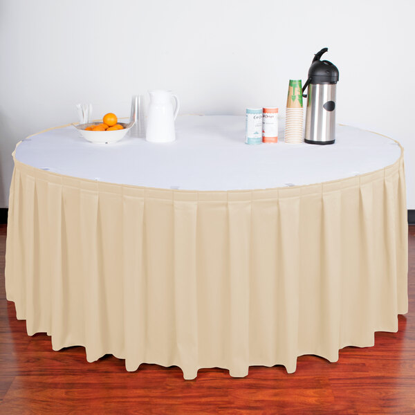 A table with a Snap Drape cream box pleat table skirt with Velcro clips on it.