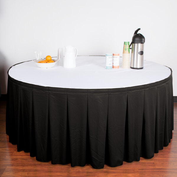 A table with a black Snap Drape continuous pleat table skirt with Velcro clips on it.