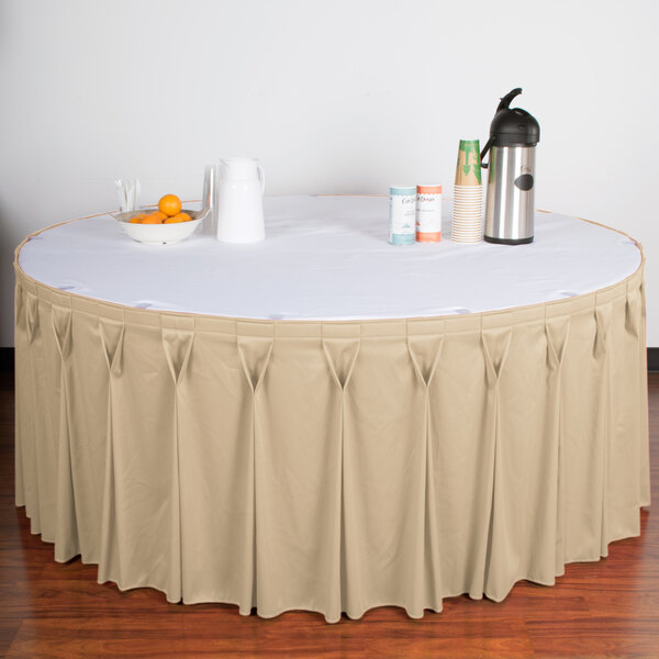 A table with a cream Snap Drape Wyndham table skirt on it with Velcro clips.