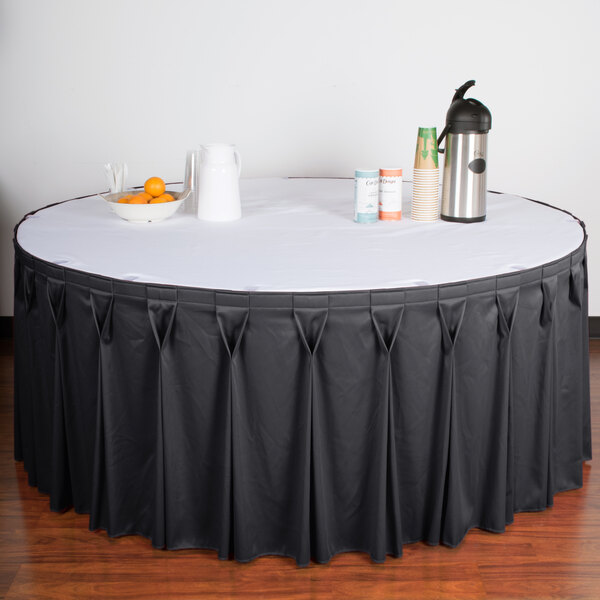 A table with a slate blue Snap Drape Wyndham table skirt on a white table with a bowl of oranges.