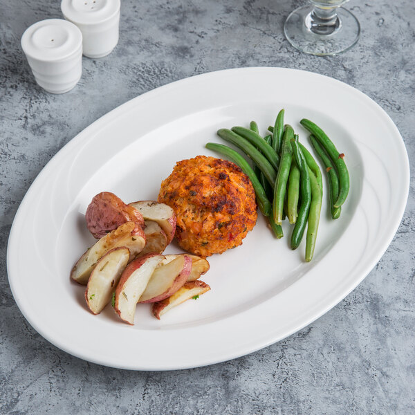 A Libbey white porcelain platter with meatballs, potatoes, and green beans on a table.