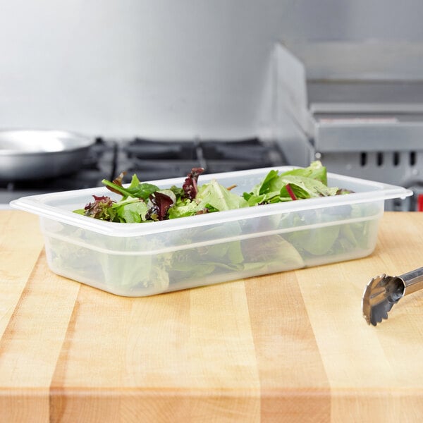 A translucent plastic food pan with lettuce in it.