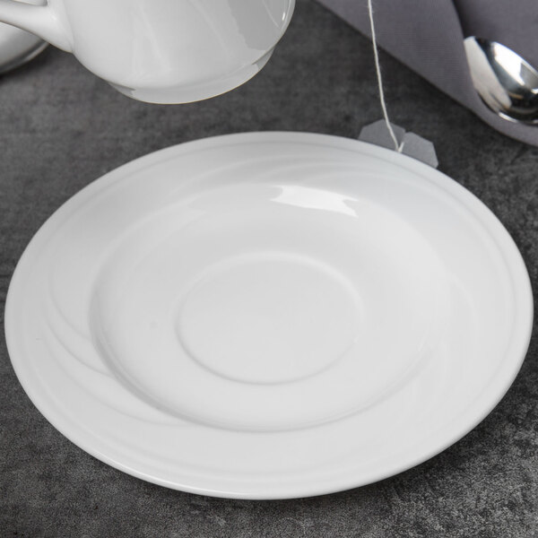 A Libbey white porcelain tea saucer with a tea bag on it.