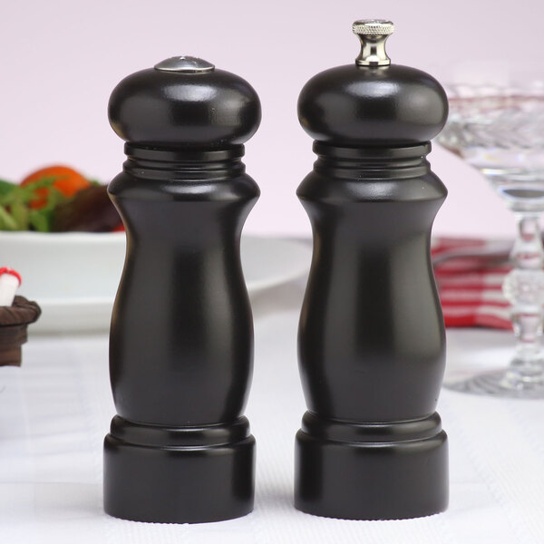 A black pepper mill and salt shaker on a table.