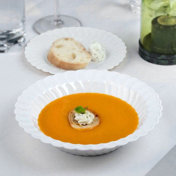 A white Fineline Flairware plastic bowl of soup with bread on top.