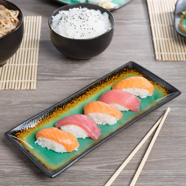 A Libbey stoneware platter with sushi and chopsticks on a table.