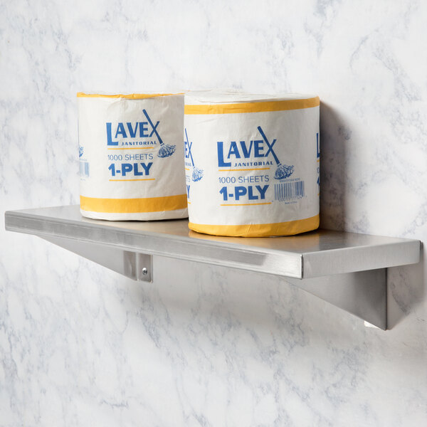A roll of toilet paper on a Bobrick stainless steel wall shelf.