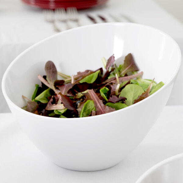 An American Metalcraft white melamine bowl filled with salad on a table.
