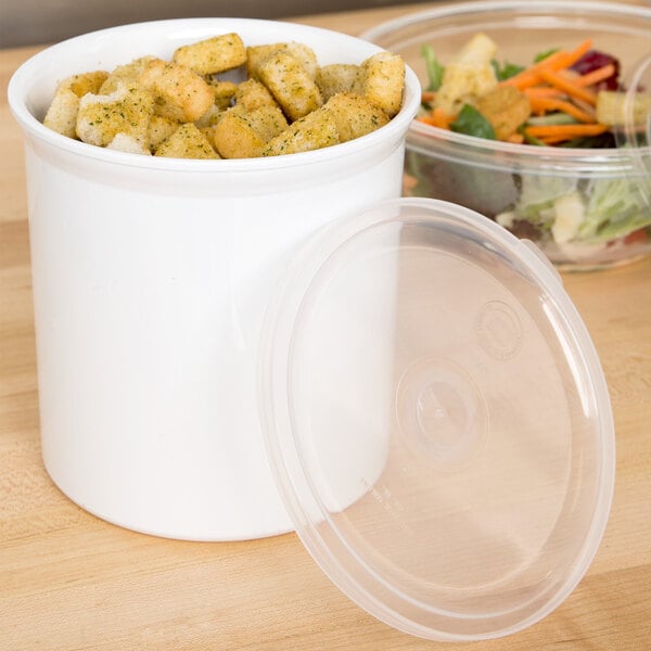 A white Carlisle plastic crock filled with croutons on a table.