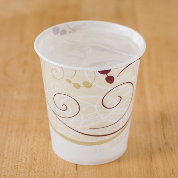 A Solo wax treated paper cold cup with a swirl design on a table.