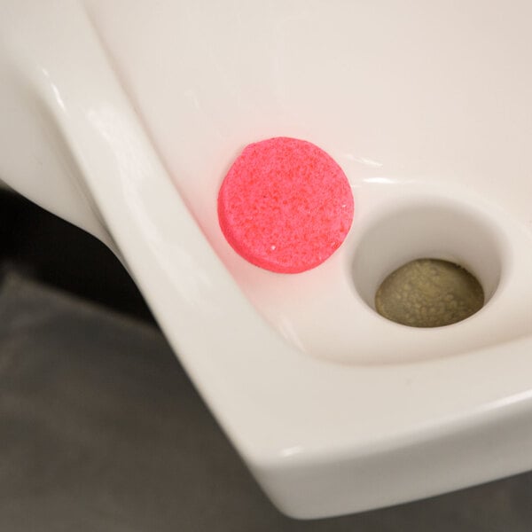 A white toilet bowl with a pink Lavex urinal cake in it.