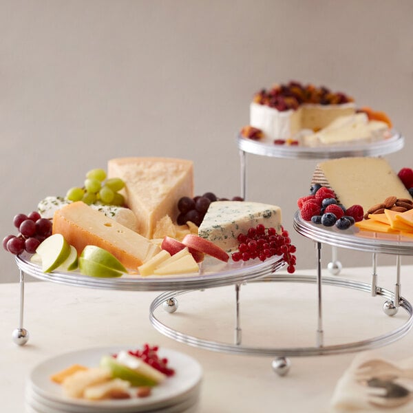 A Wilton three-tiered display stand holding cheese and fruit on a table.
