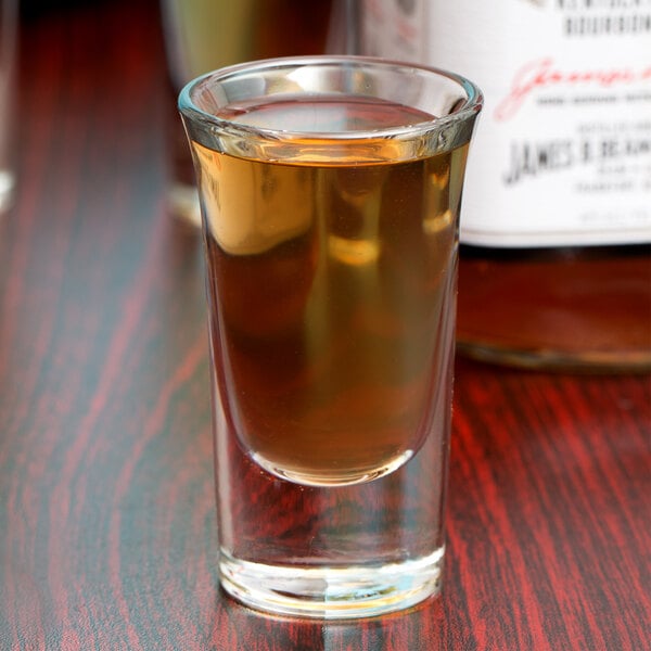 A Libbey tall shot glass filled with brown liquid.