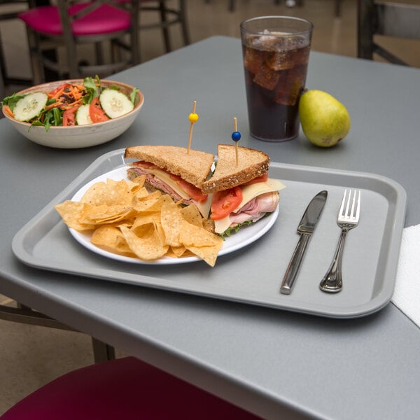 A Carlisle fast food tray with a sandwich, chips, and a drink on it.