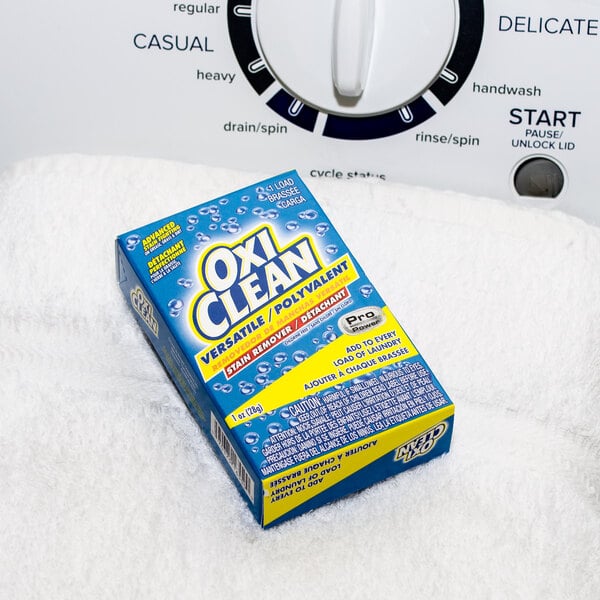 An OxiClean box for coin vending machines sitting on a towel atop a washing machine.