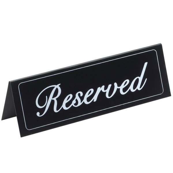 A black double-sided vinyl "Reserved" sign on a table.