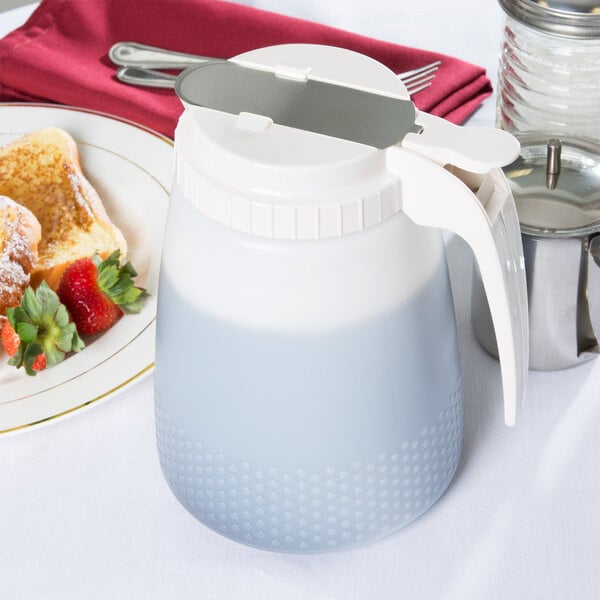 A white Tablecraft dispenser filled with liquid on a table next to food.
