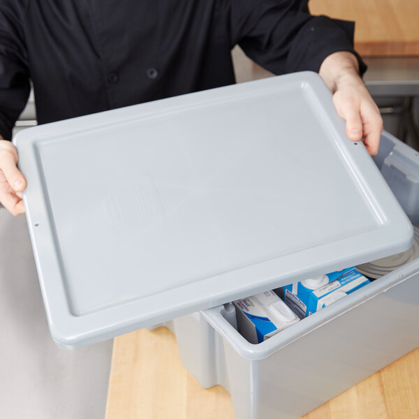 A man holding a Rubbermaid tote box lid on a tote box.