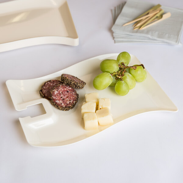 A Fineline ivory plastic cocktail plate with a stemware hole holding a variety of foods.