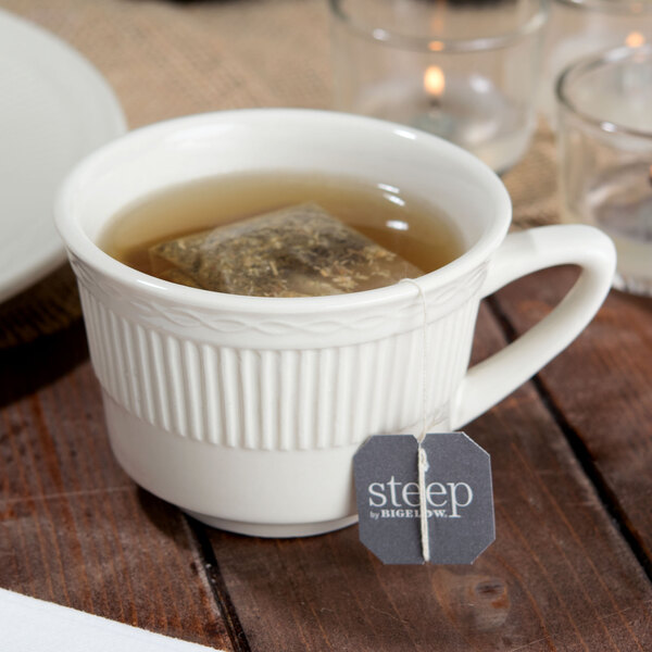 An Ivory embossed china short cup filled with tea and a tea bag.