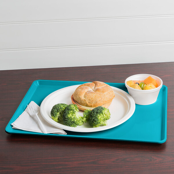 A Cambro dietary tray with a sandwich, broccoli, and fruit on it.