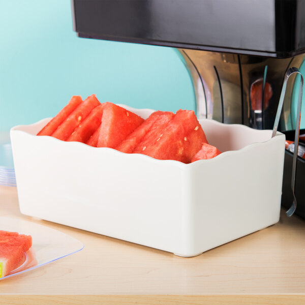 A white deli crock filled with slices of watermelon.
