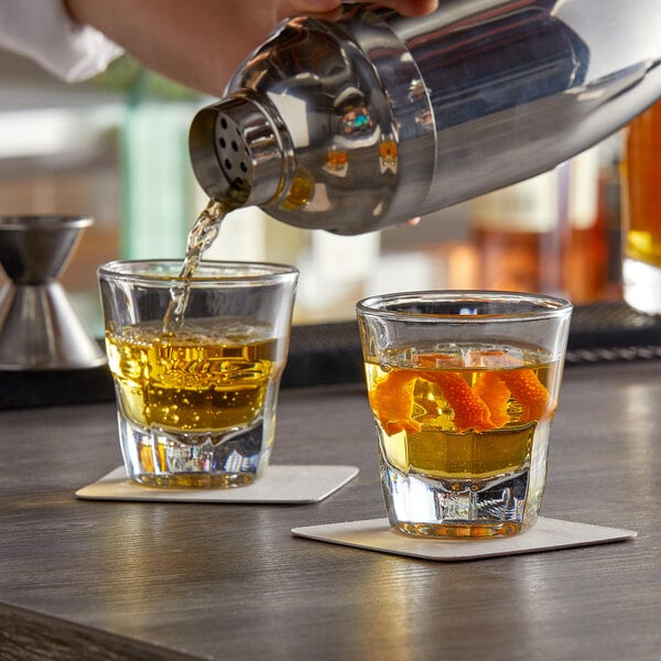 A person pouring espresso into two Anchor Hocking espresso glasses on a table.
