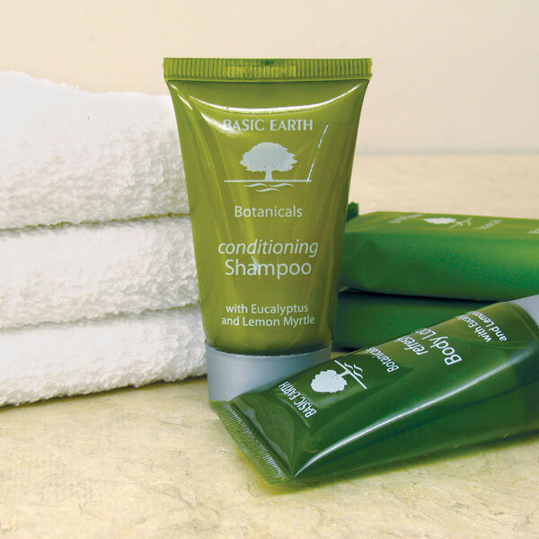 A green bottle of Basic Earth Botanicals Conditioning Shampoo next to a stack of towels.