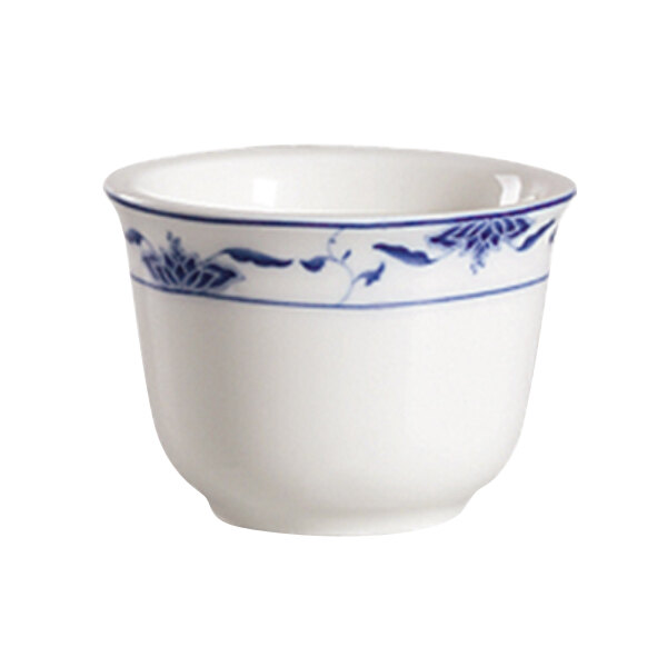 A close-up of a white bone porcelain sake cup with a blue lotus design on the rim.