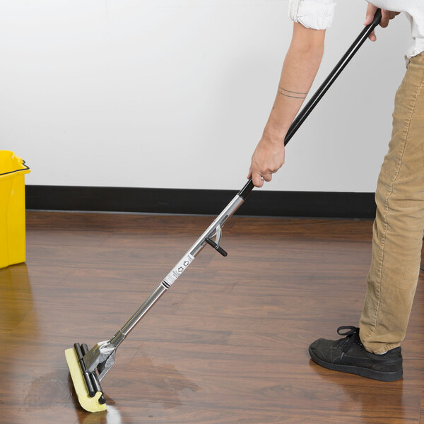 A person using a Rubbermaid Cellulose Sponge Mop to clean a wood floor.