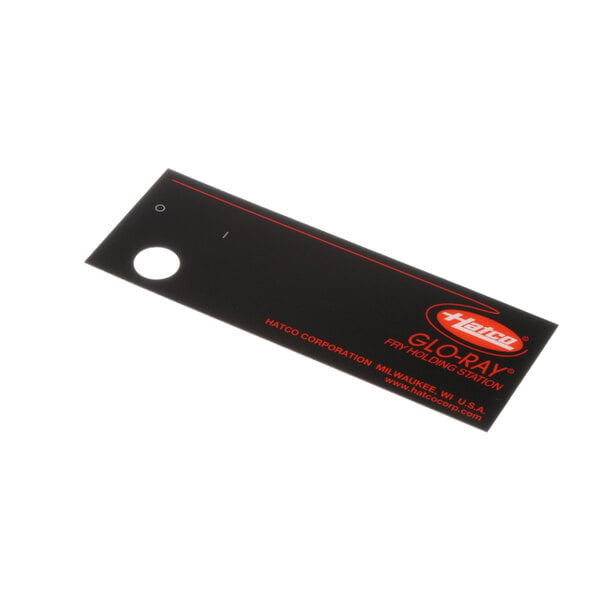 A black rectangular plastic decal with orange and red text.