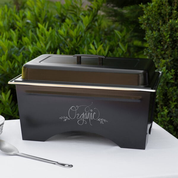 A black and brown rectangular Sterno chafing dish with a silver spoon inside.