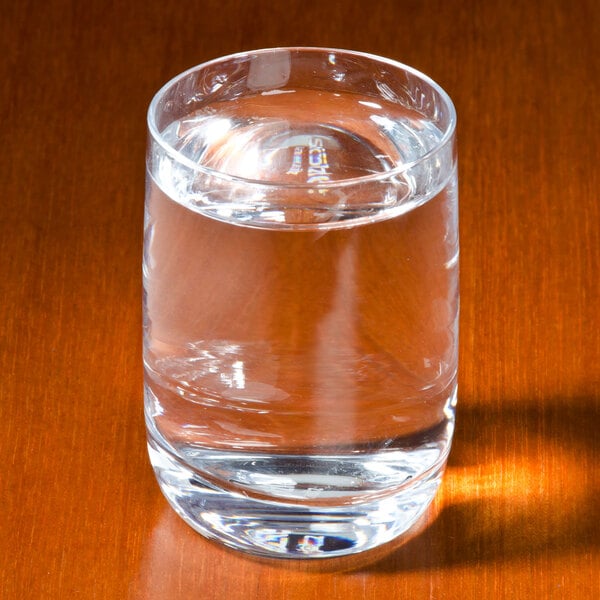 A Stolzle Weinland shot glass filled with water on a table.