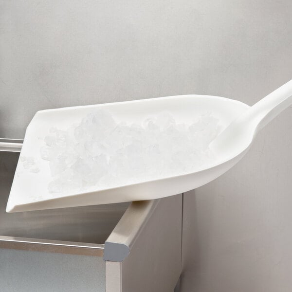 A white Carlisle Sparta ice shovel with ice in it.