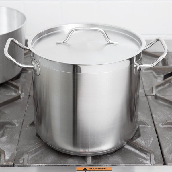 A large silver Vollrath stainless steel stock pot with a lid on a stove.
