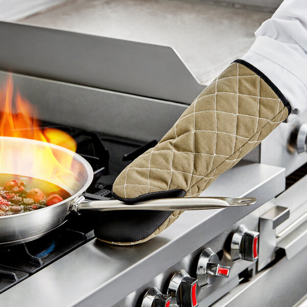 A person using a San Jamar puppet style oven mitt to cook on a stove.