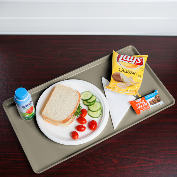 A Cambro desert tan dietary tray with a sandwich, vegetables, and a drink on it.