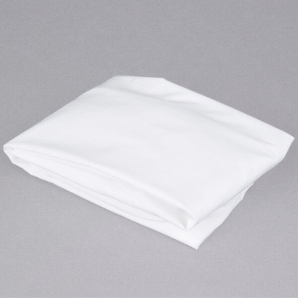 A folded white L.A. Baby crib sheet on a gray surface.