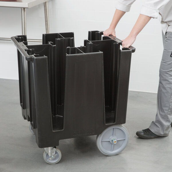 A person pushing a large black Cambro dish caddy.