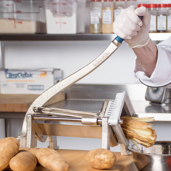 A person using a Vollrath French Fry Cutter to cut potatoes on a counter.