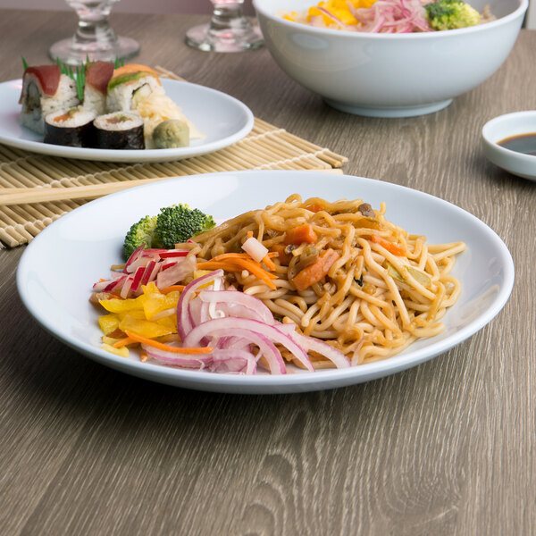 A plate of noodles and vegetables with chopsticks on a table.