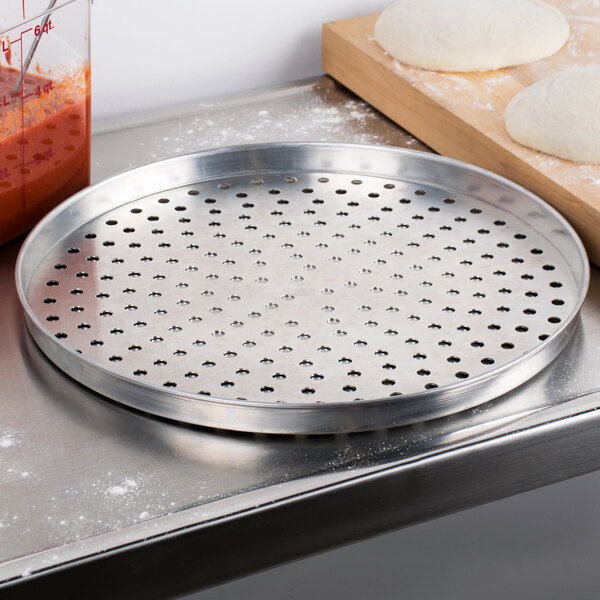 An American Metalcraft perforated aluminum pizza pan on a counter.