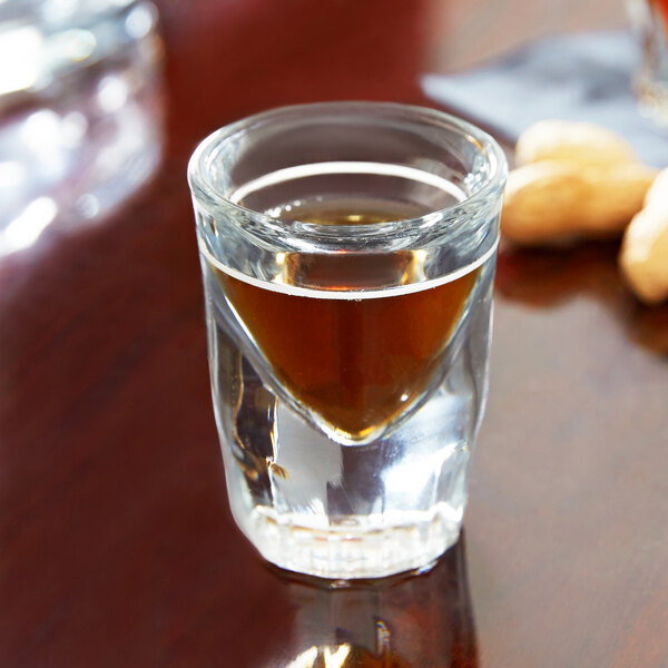 An Anchor Hocking fluted shot glass with a brown liquid in it.